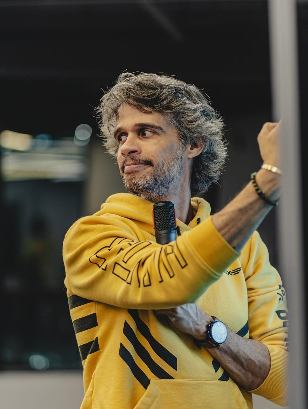 Marcos Strider de moletom amarelo, com o microfone na mão
